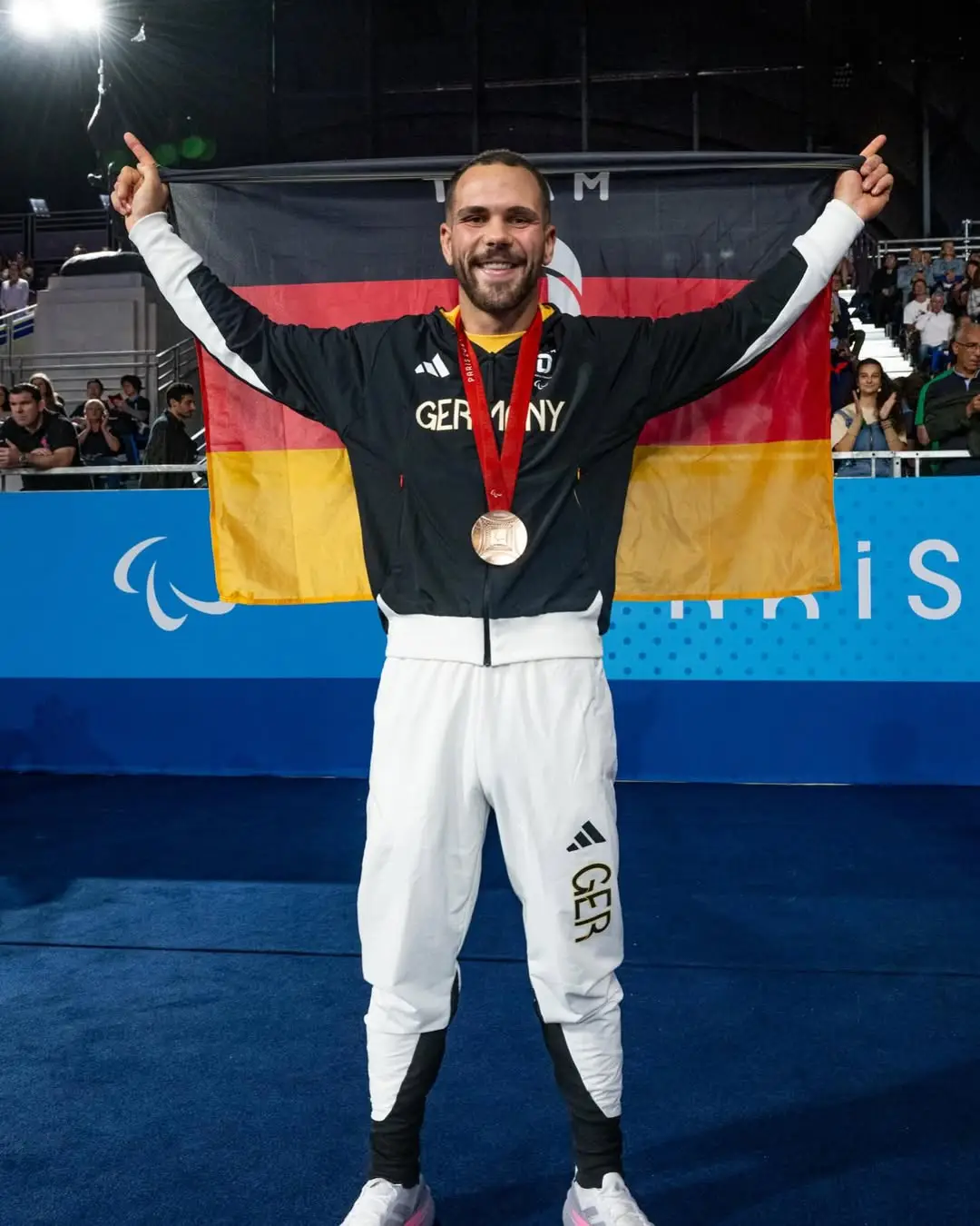 Lennart Sass mit Bronzemedaille und Deutschland-Flagge bei den Paralympics in Paris